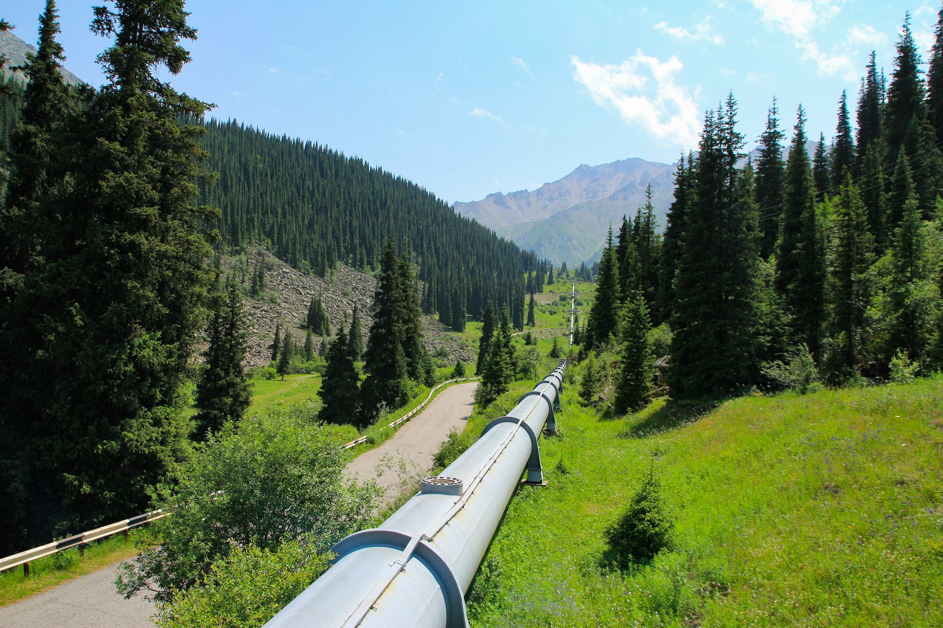 A pipeline running through lush green mountains — the water infrastructure United Current helps you sell into